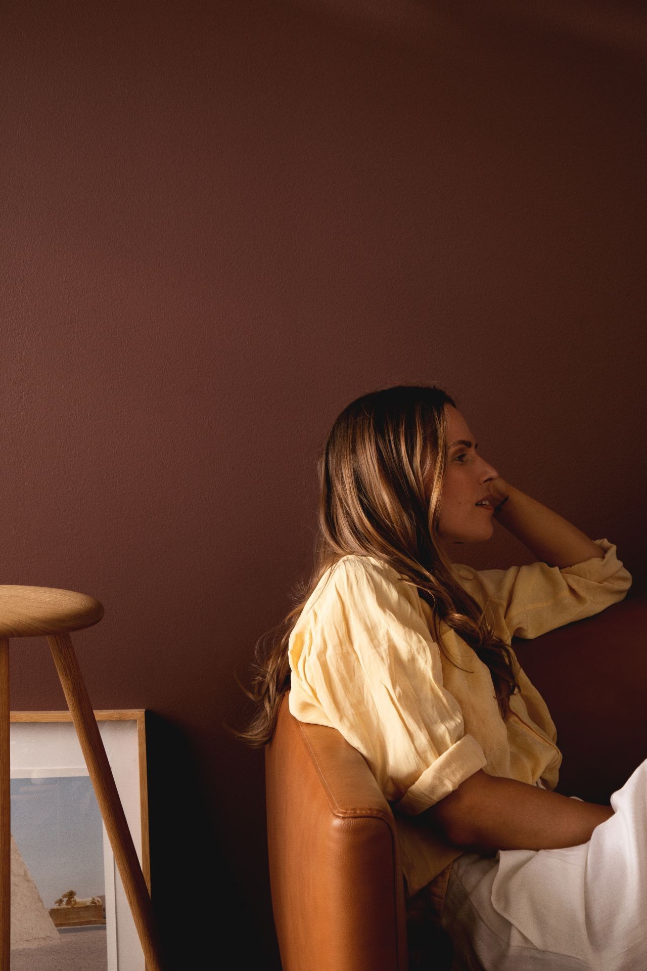 woman sitting on sofa in front of warm brown colour wall