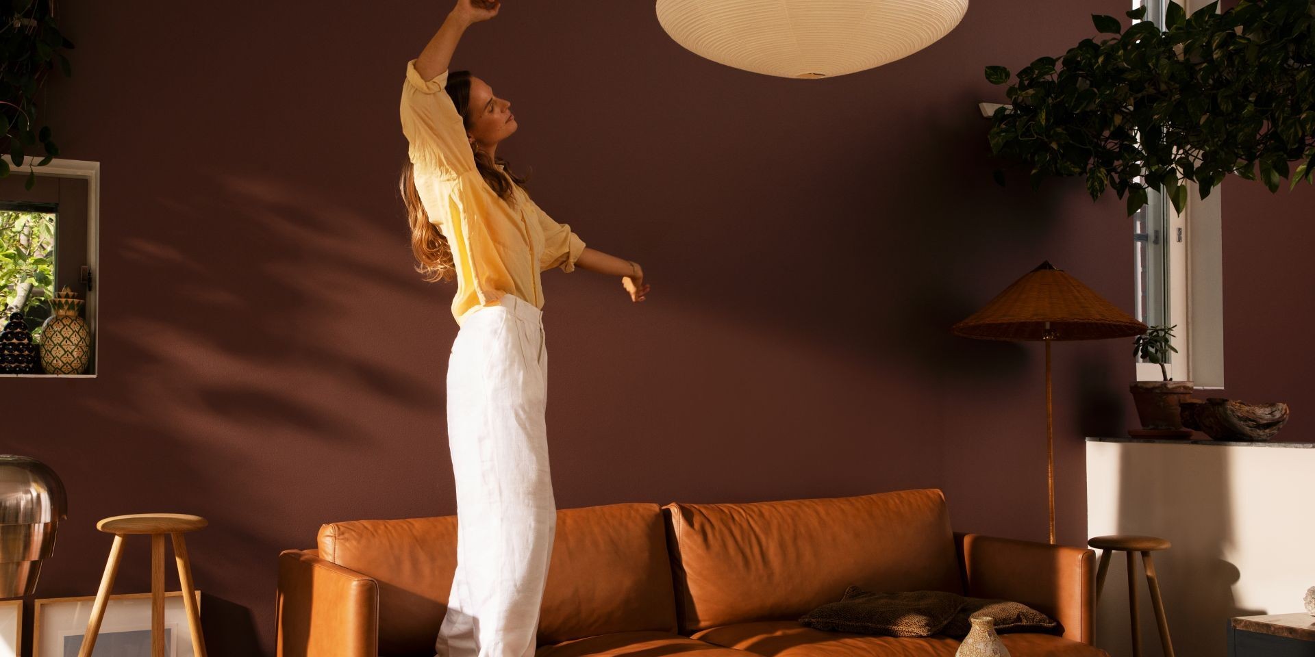 woman dancing in cosy living room with warm brown colour wall and sofa