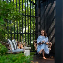 melna koka mājas fasāde sieviete uz soliņa