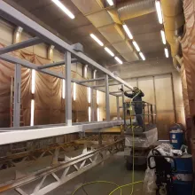 Person spraying paint on metal structure