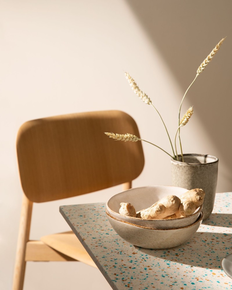 Beige wall, wooden chair and earthy colour tableware on dinner table