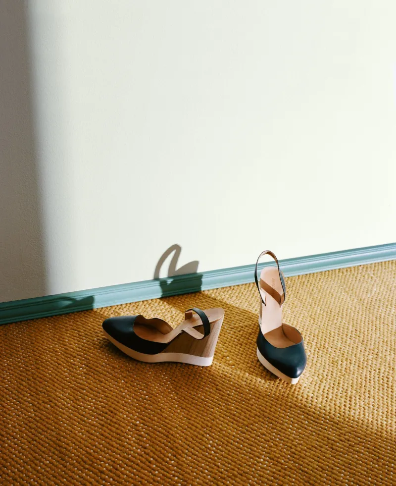 sandals on brown jute mat near soft blue-green skirting board