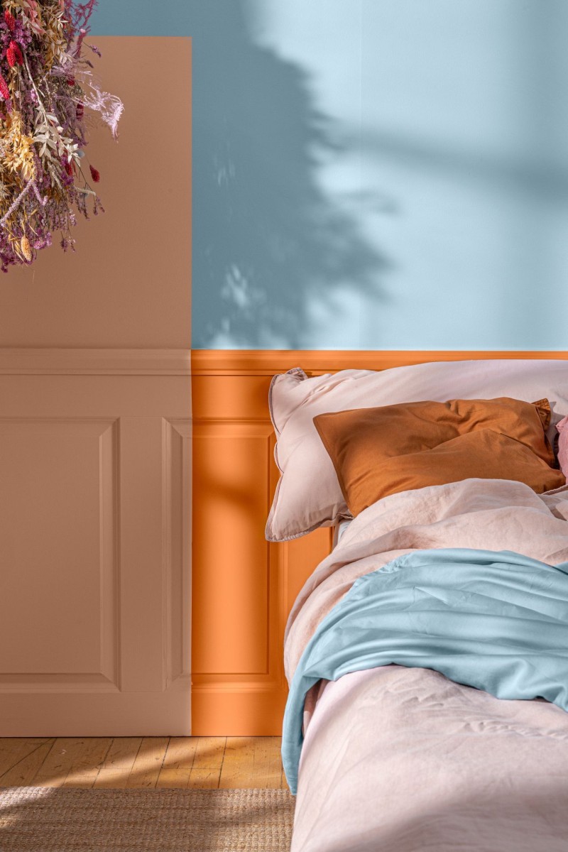 bedroom with blue colour wall and different orange shades on bed headboard 